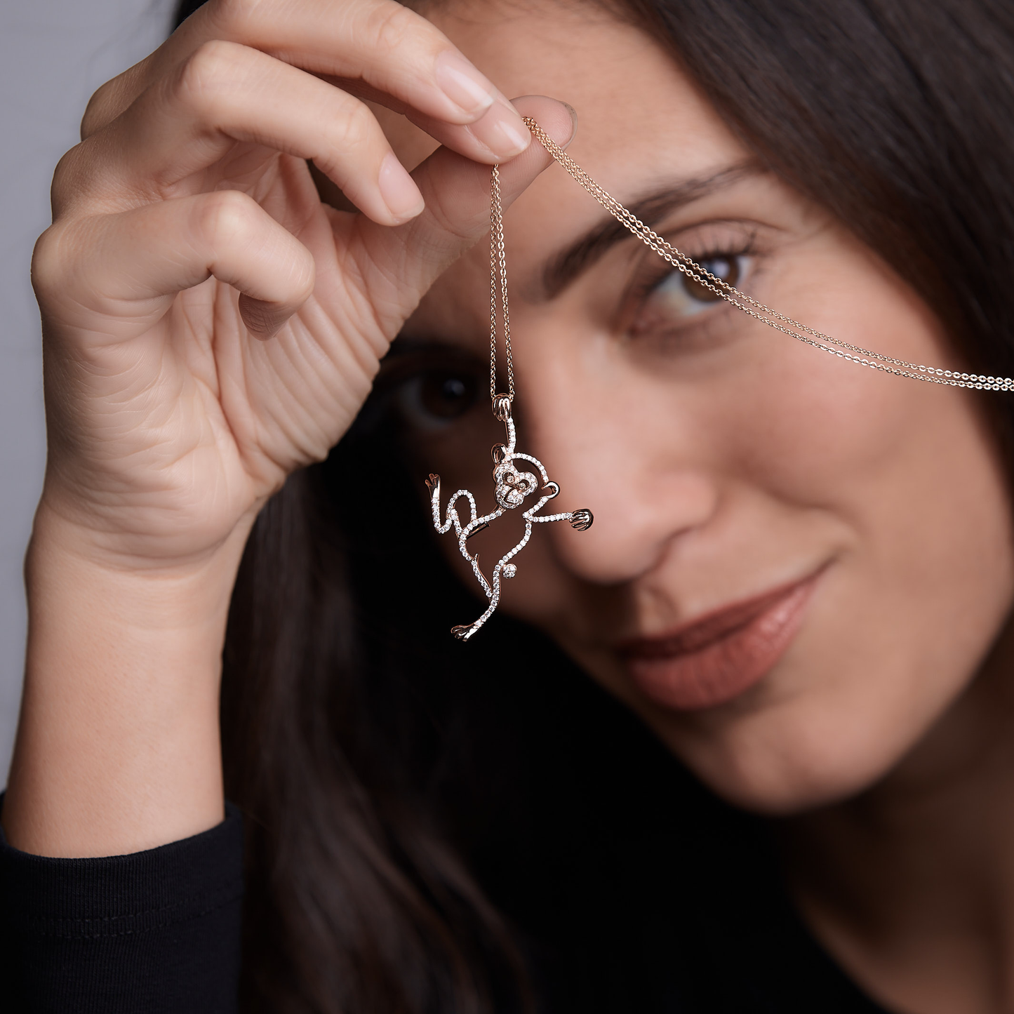 Woman showing Oliver Heemeyer diamond monkey necklace made of 18k rose gold.