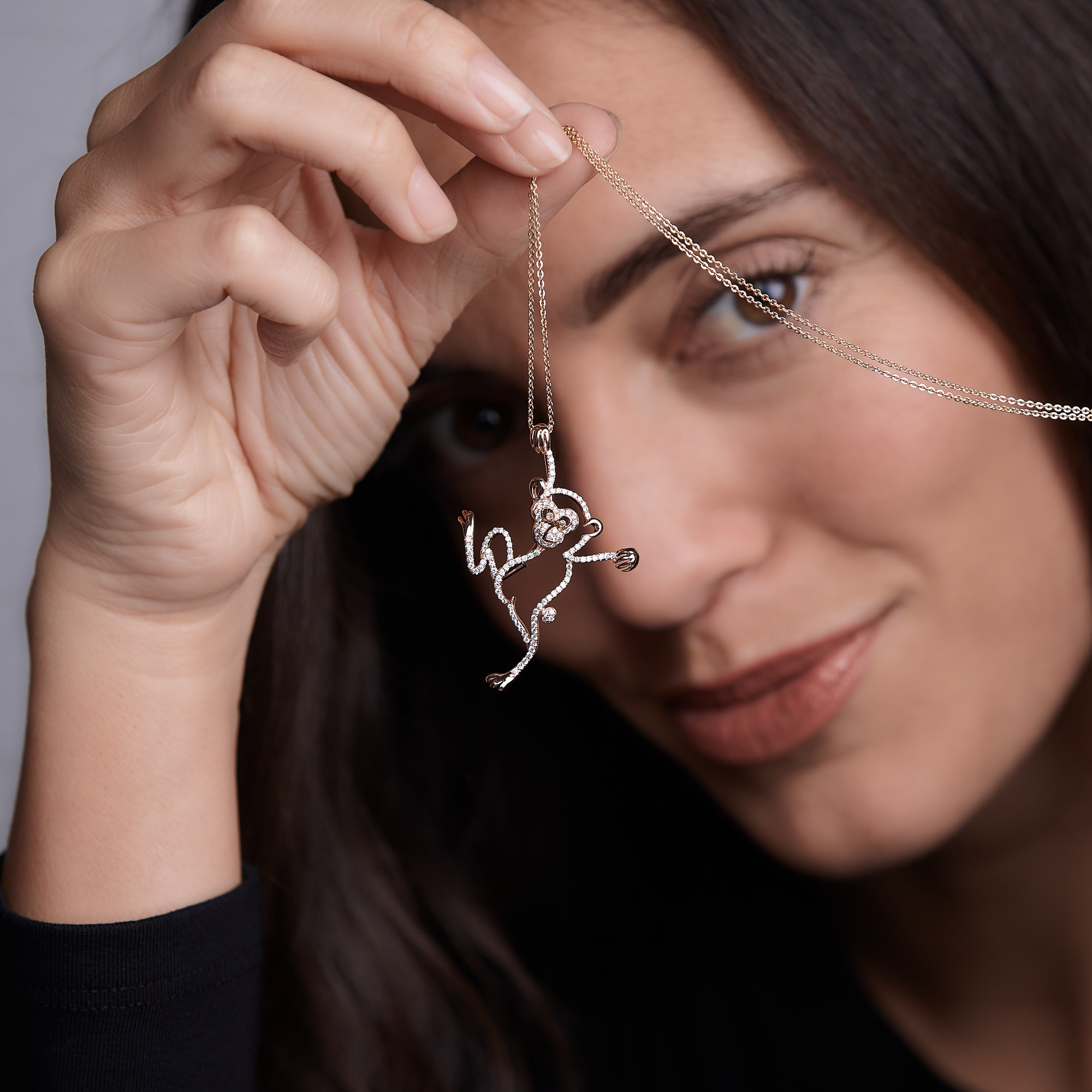 Woman showing Oliver Heemeyer diamond monkey necklace made of 18k rose gold.