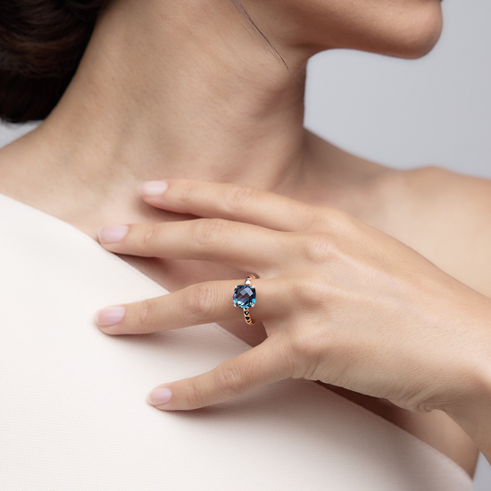 Woman wearing the Charlie London Blue Topaz Ring made of 18k rose gold.