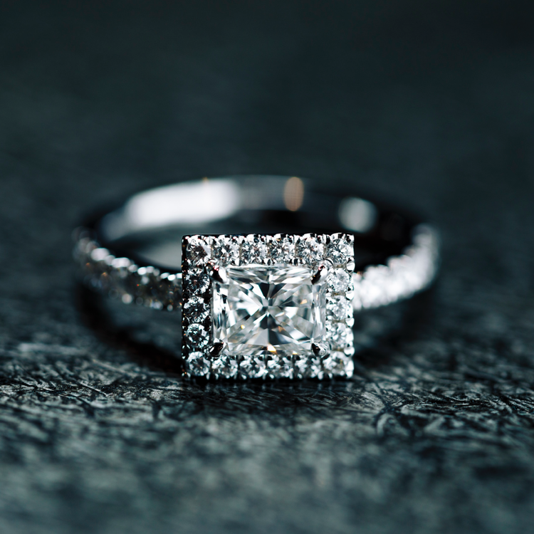 Handcrafted and made of 18k white gold, the Oliver Heemeyer Mara engagement half-circle ring features a pavé-set diamond halo that encompasses a rectangular cut center diamond.