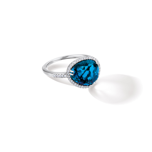 Oliver Heemeyer Cocktail diamond ring carrying a colourful topaz in its center, framed with sparkling diamonds and made of 18k white gold. Stone colour: London blue