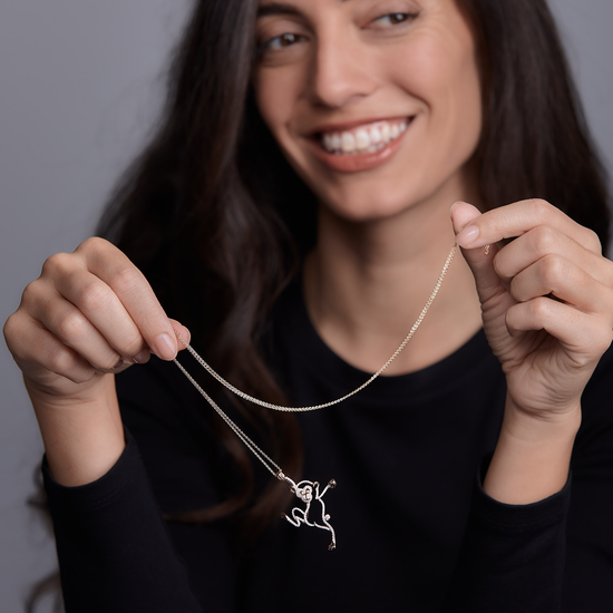 Woman showing Oliver Heemeyer diamond monkey necklace made of 18k rose gold. Different perspective.
