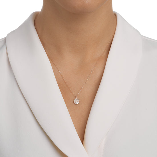 Woman wearing the Oliver Heemeyer round tag diamond pendant made of 18k rose gold.