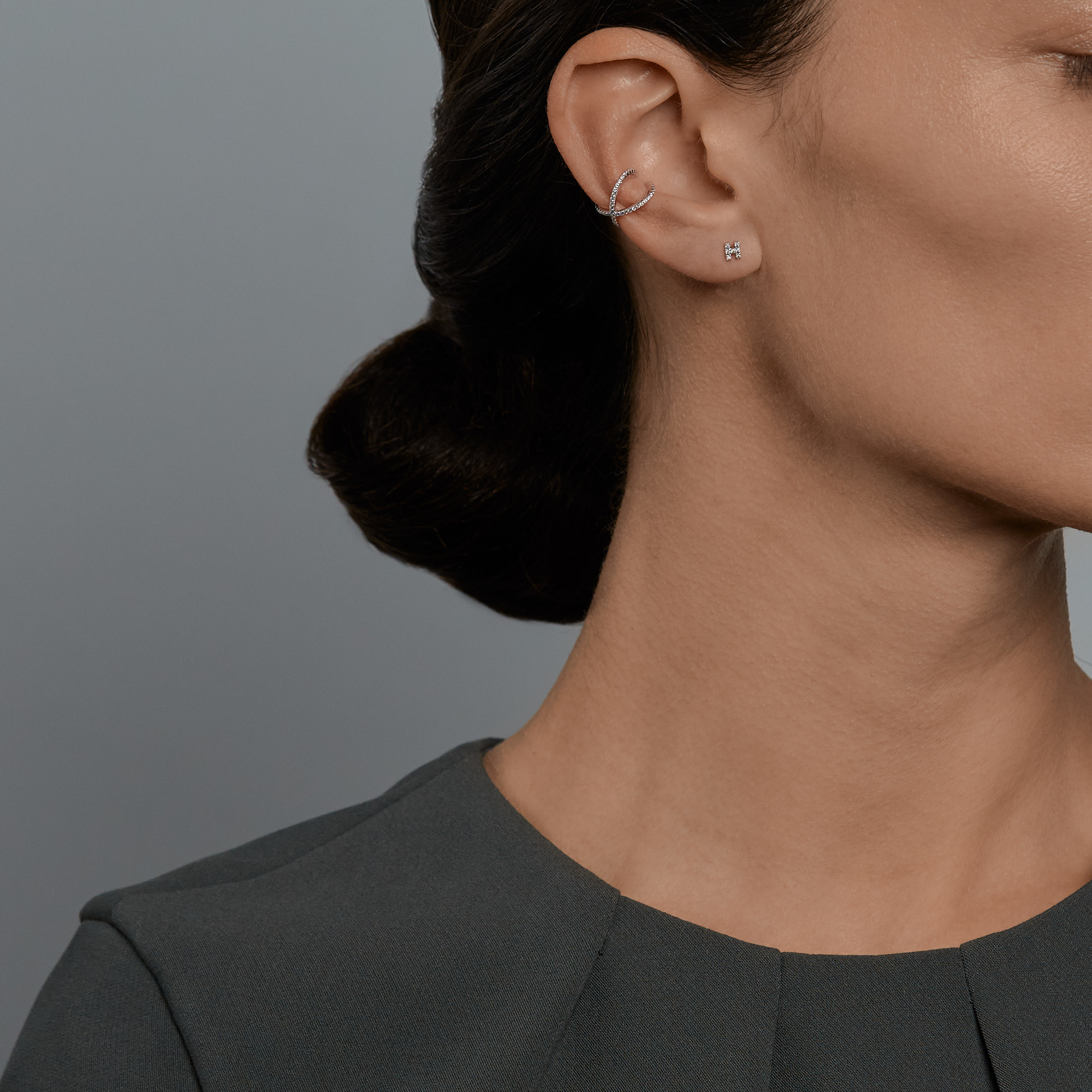Woman wearing the Oliver Heemeyer Orbit Diamond Ear Cuff and Letter diamond ear stud 'H' made of 18k white gold.