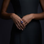 Woman wearing the Oliver Heemeyer Audra ring carrying a purplish-blue tanzanite in its center, framed by diamonds. This stunning design is handcrafted of 18k rose gold and made for special moments. Front perspective.