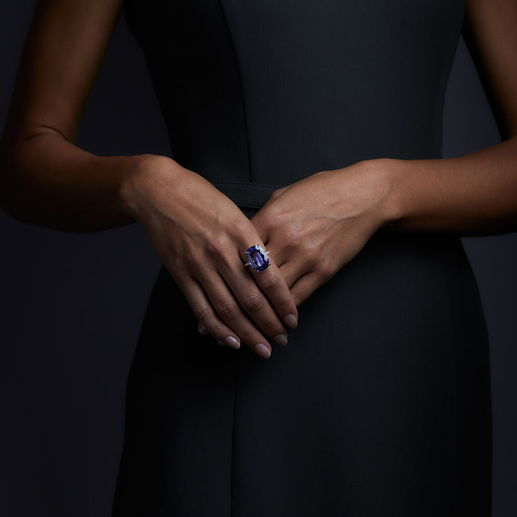 Woman wearing the Oliver Heemeyer Audra ring carrying a purplish-blue tanzanite in its center, framed by diamonds. This stunning design is handcrafted of 18k rose gold and made for special moments. Front perspective.
