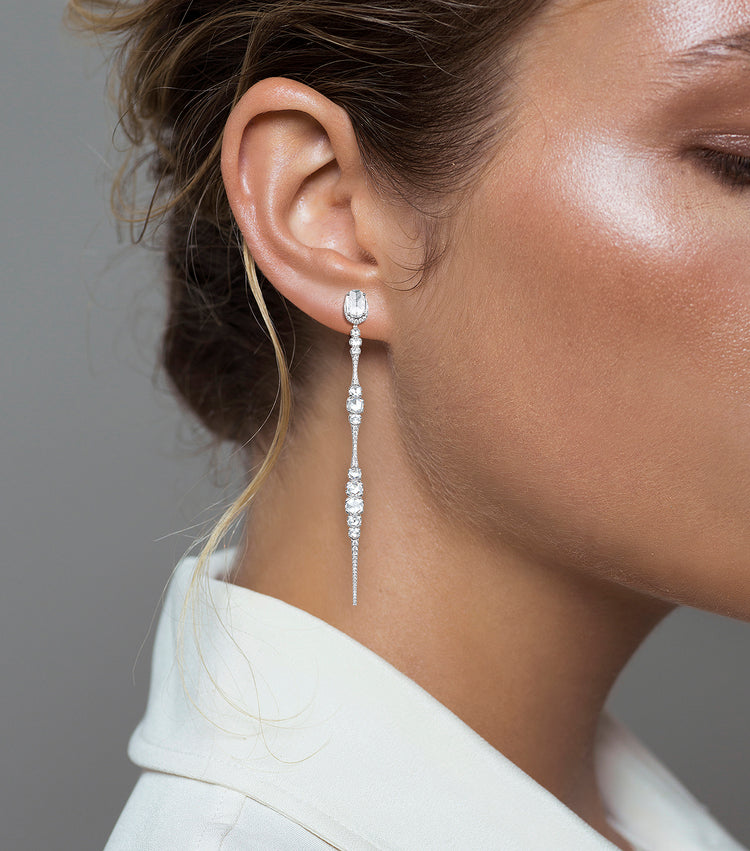 Woman wearing the Oliver Heemeyer 18k white gold Ice earrings, designed in the shape of a icicle and adorned with diamonds.
